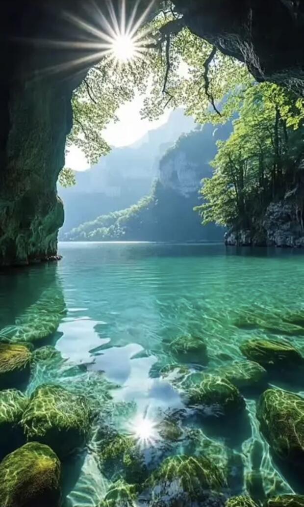 Sunlight streaming through a cave opening above still turquoise water